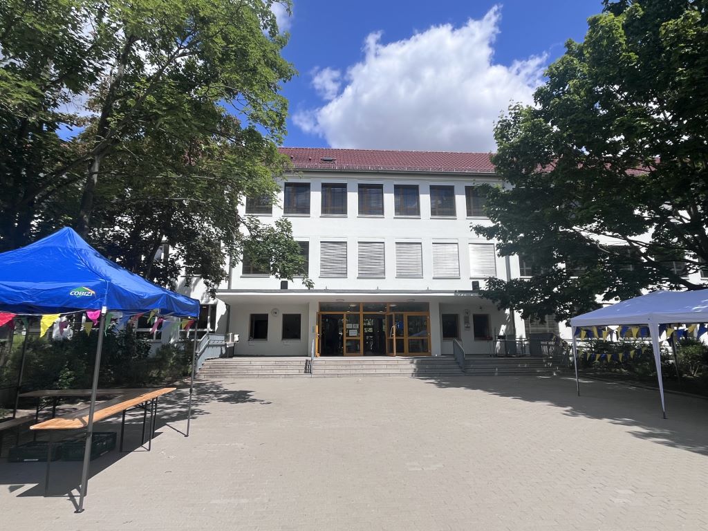 Schulhof mit Pavillons vor dem Schulgebäude