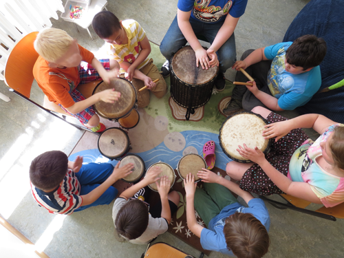Kindergruppe sitzt im Kreis und trommelt gemeinsam