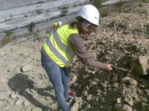 Kind mit Warnweste und Bauhelm arbeitet auf einer Baustelle