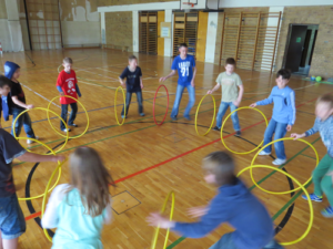 Kinder bewegen sich mit gelben Gymnastikreifen in der Turnhalle