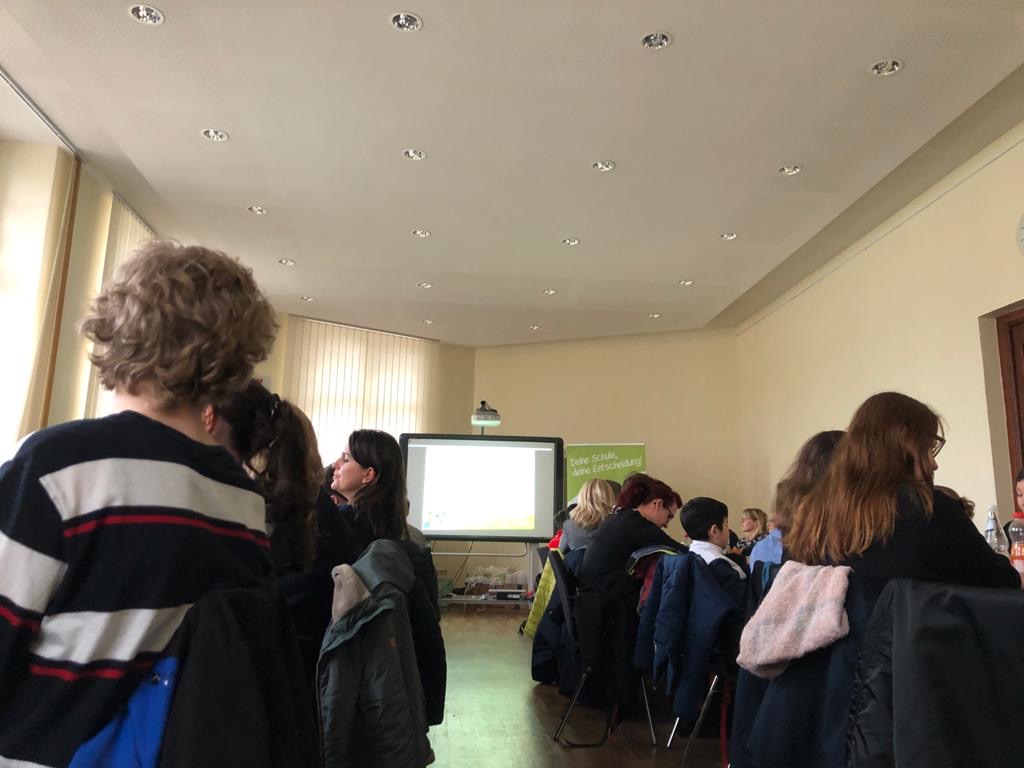 Schülergruppe vor einer Präsentationsleinwand
