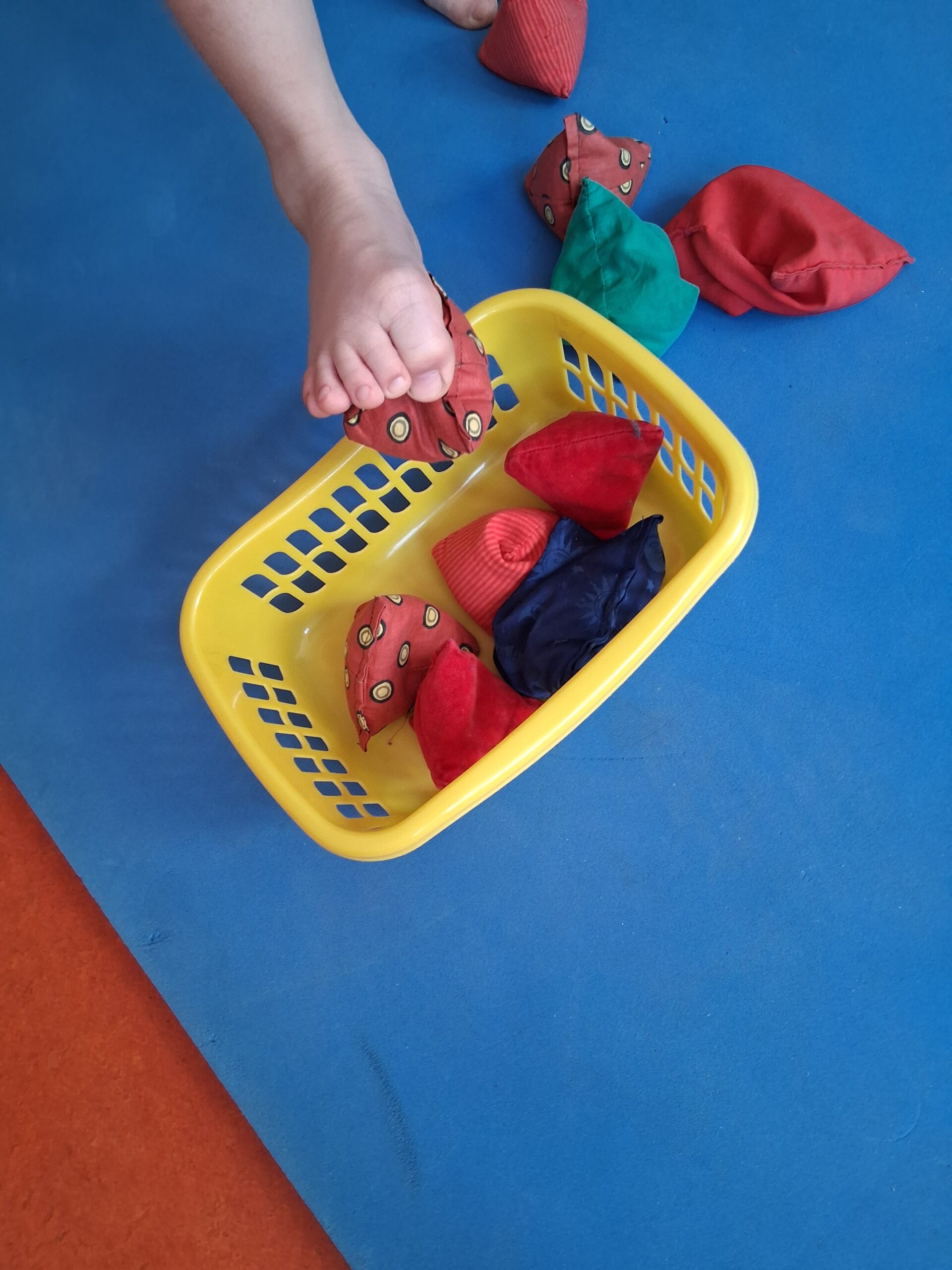 Kind sortiert bunte Knetstücke in einen Korb