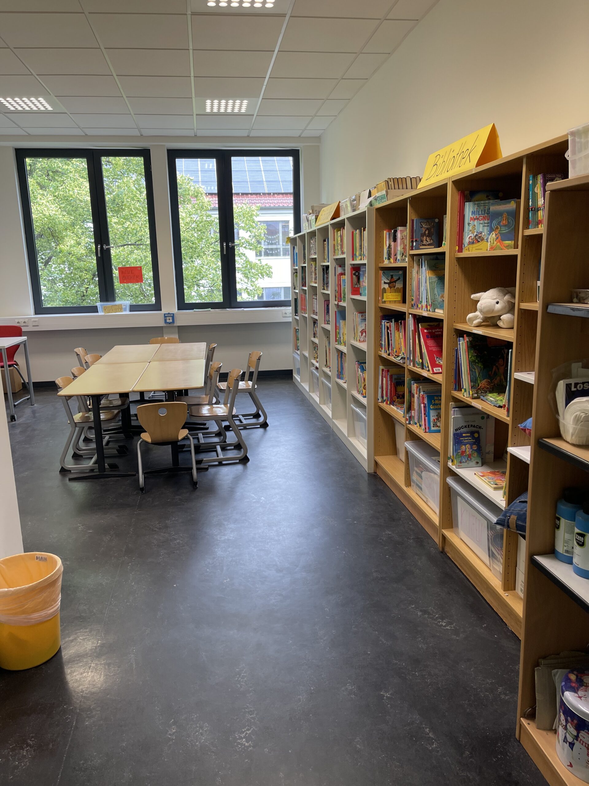 Blick in die Schulbibliothek mit Bücherregalen und Lesetischen