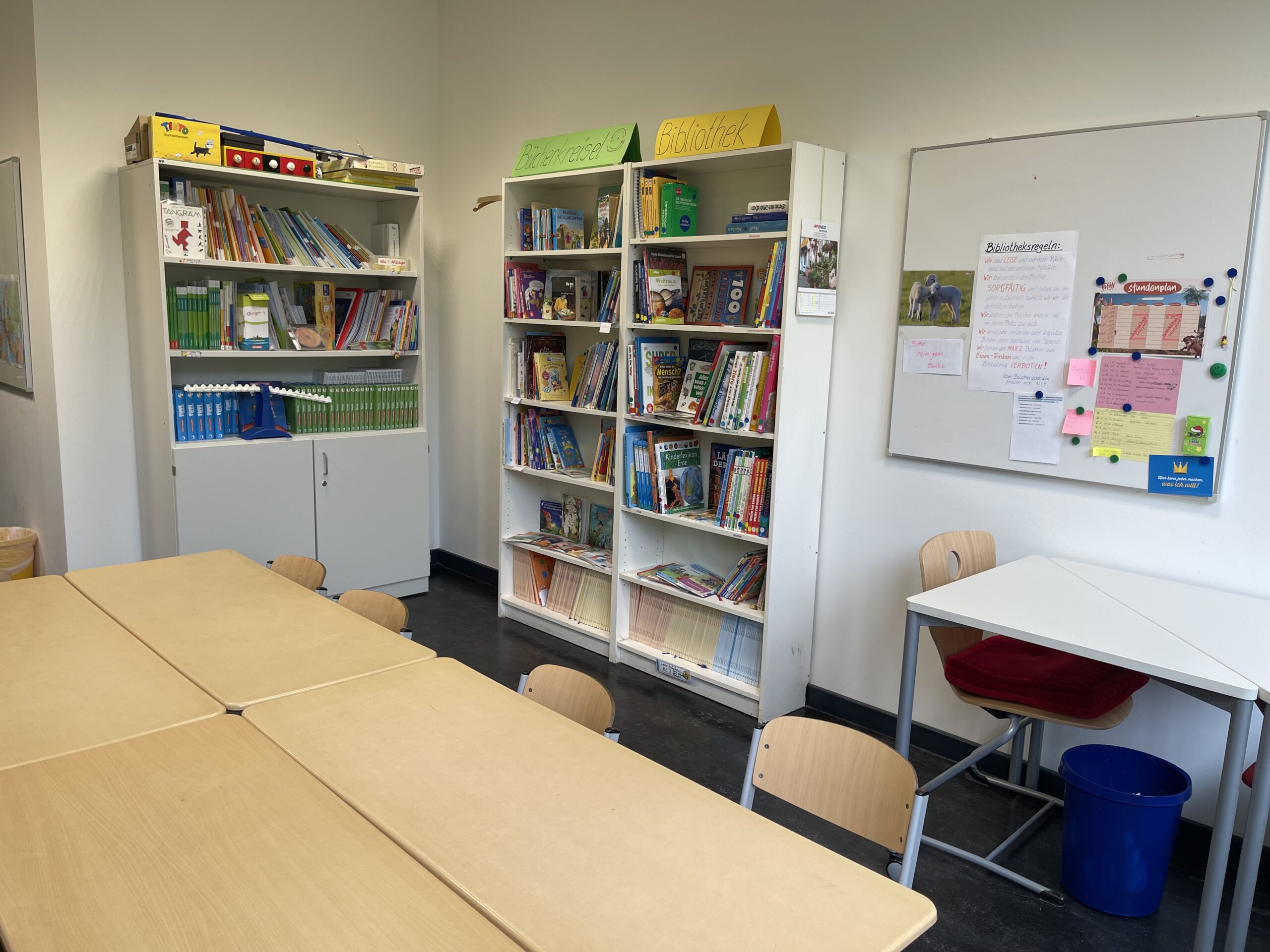 Bibliotheksraum mit Bücherregalen, Arbeitstischen und Whiteboard